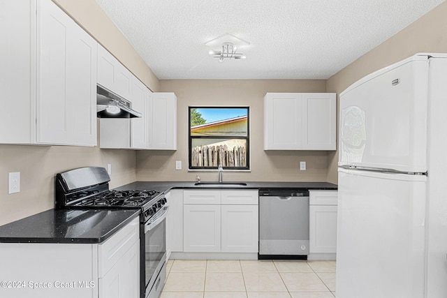 kitchen with under cabinet range hood, stainless steel appliances, a sink, white cabinetry, and dark countertops