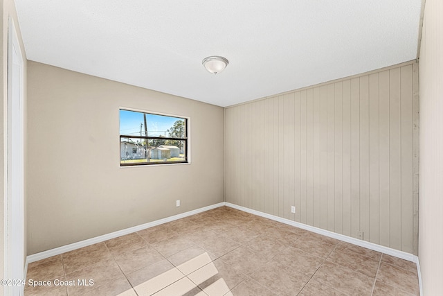 empty room with baseboards and light tile patterned flooring