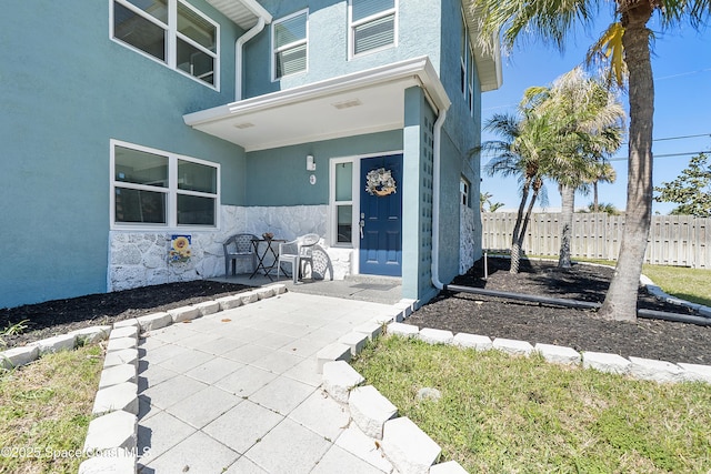 doorway to property featuring fence and stucco siding