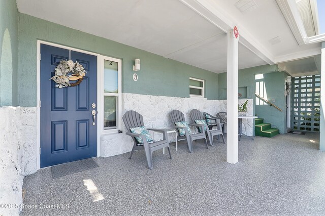 entrance to property featuring visible vents and stucco siding