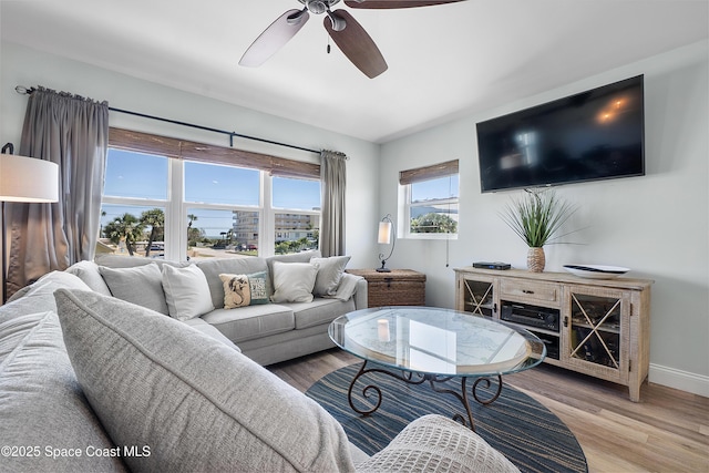 living room featuring ceiling fan, wood finished floors, and baseboards