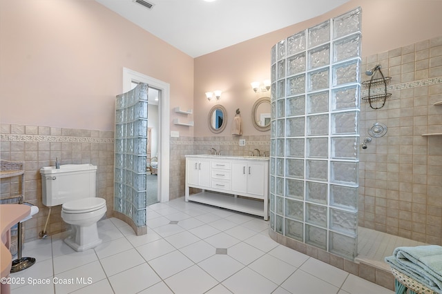 full bathroom featuring a walk in shower, a sink, tile walls, wainscoting, and tile patterned floors