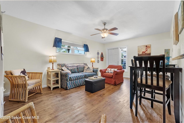 living area with ceiling fan, baseboards, and wood finished floors