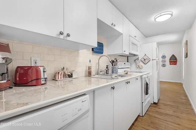 kitchen featuring white appliances, tasteful backsplash, white cabinets, light wood-style floors, and a sink