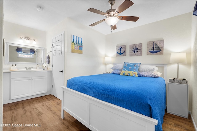 bedroom with a sink, ensuite bath, a ceiling fan, and wood finished floors