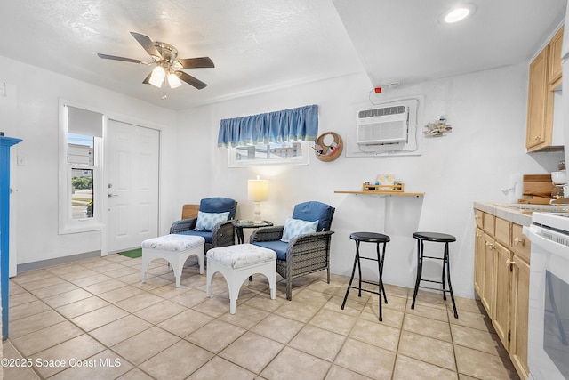 sitting room with light tile patterned floors, ceiling fan, and a wall mounted air conditioner