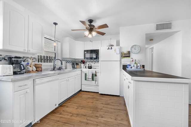 kitchen with white appliances, visible vents, ceiling fan, a peninsula, and white cabinetry