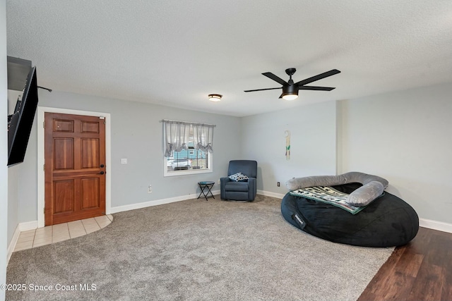 sitting room with a textured ceiling, carpet floors, a ceiling fan, and baseboards