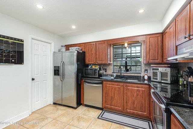 kitchen featuring tasteful backsplash, dark stone counters, appliances with stainless steel finishes, a sink, and recessed lighting