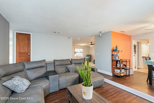 living room featuring visible vents, a textured ceiling, a ceiling fan, and wood finished floors