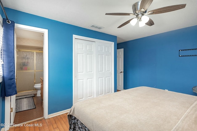 bedroom featuring a closet, visible vents, a ceiling fan, wood finished floors, and baseboards