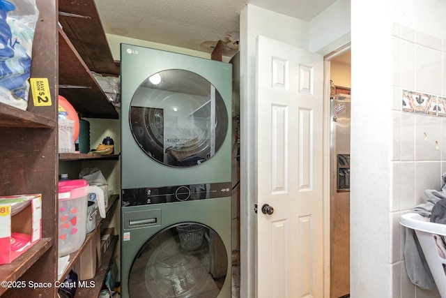 laundry area with a textured ceiling, laundry area, and stacked washer and clothes dryer