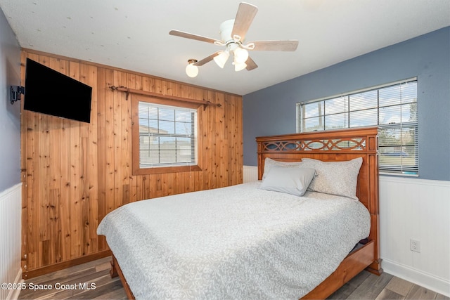 bedroom with wainscoting, wood finished floors, and wooden walls