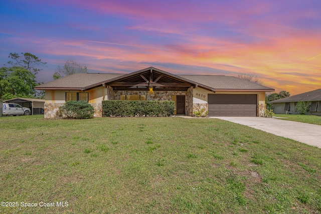 view of front of property with concrete driveway, stone siding, an attached garage, a front yard, and stucco siding