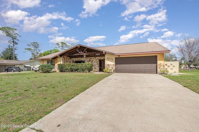 view of front of property with a front yard, stone siding, an attached garage, and concrete driveway