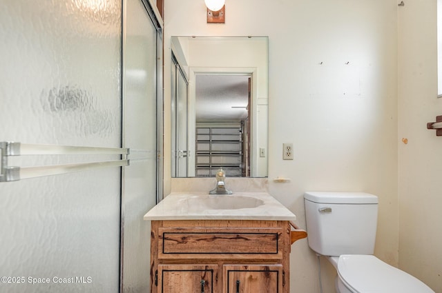 bathroom with a shower with shower door, vanity, and toilet