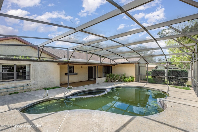 view of swimming pool featuring glass enclosure, a pool with connected hot tub, and a patio area