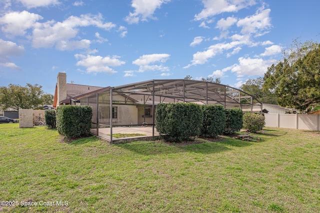 rear view of house featuring a lanai, a patio area, fence, and a yard