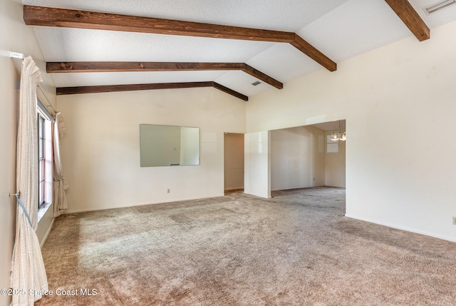 unfurnished room with carpet, visible vents, lofted ceiling with beams, and a textured ceiling