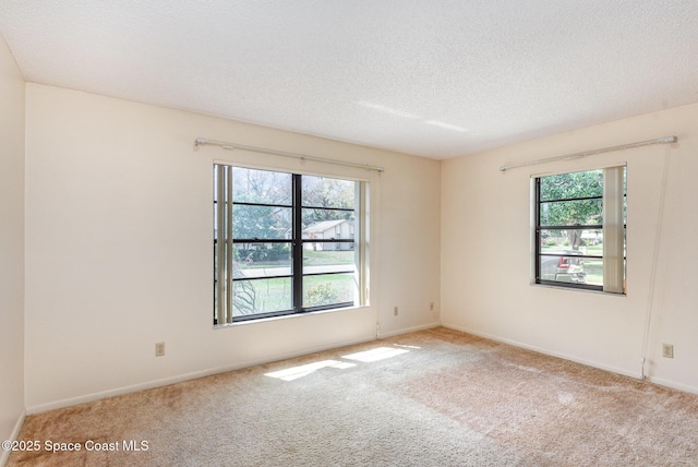 carpeted spare room with a textured ceiling and baseboards