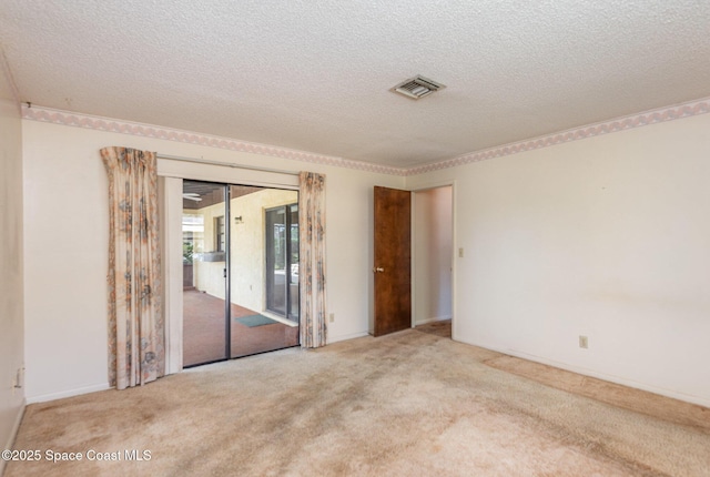 carpeted spare room featuring visible vents and a textured ceiling