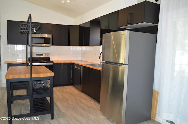 6110 Grissom Pkwy, Cocoa, FL 32927 - kitchen featuring appliances with stainless steel finishes, a sink, wooden counters, lofted ceiling, and backsplash