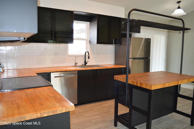 6110 Grissom Pkwy, Cocoa, FL 32927 - kitchen with a sink, dark cabinets, wood counters, stainless steel appliances, and decorative backsplash