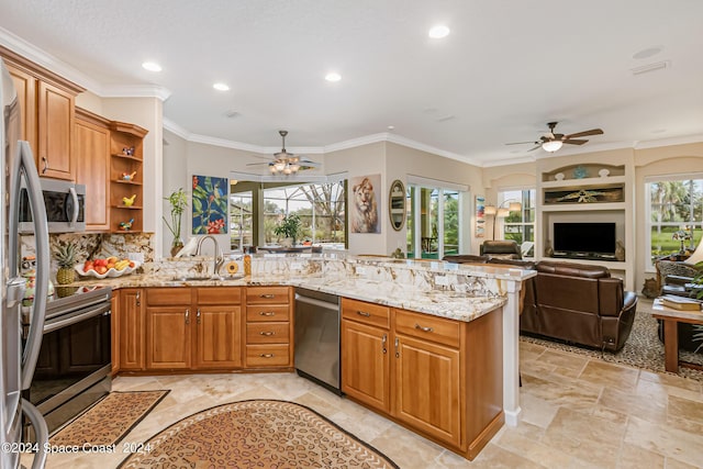 kitchen featuring plenty of natural light, appliances with stainless steel finishes, a peninsula, light stone countertops, and a sink