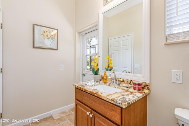 half bath with vanity, toilet, and baseboards