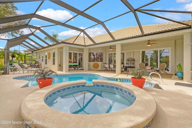 view of pool featuring glass enclosure, ceiling fan, a pool with connected hot tub, and a patio