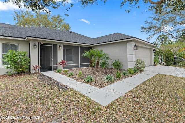 view of front of home featuring stucco siding, a shingled roof, concrete driveway, an attached garage, and a sunroom