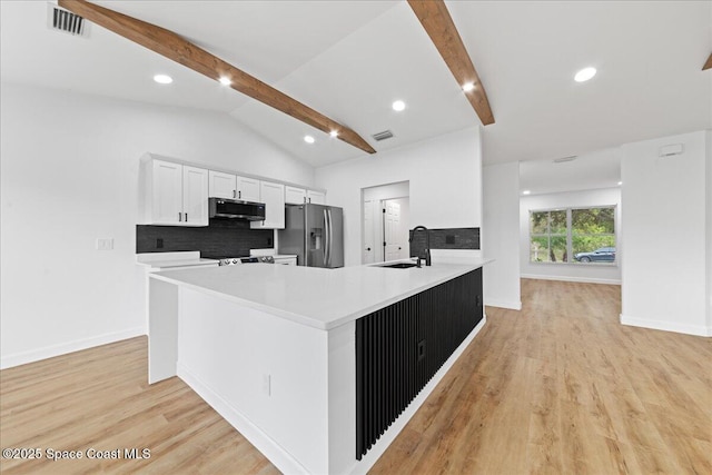 kitchen with visible vents, lofted ceiling with beams, light wood-style flooring, stainless steel appliances, and a sink