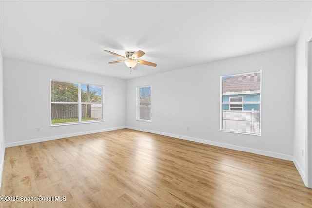 spare room featuring light wood-type flooring, ceiling fan, and baseboards