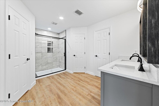 bathroom with visible vents, a stall shower, a sink, wood finished floors, and baseboards