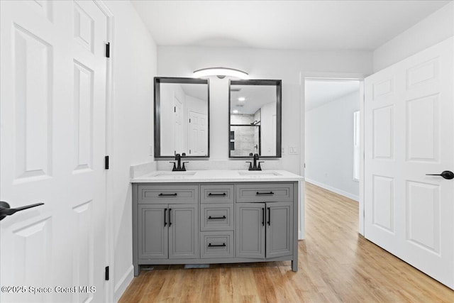 full bathroom with an enclosed shower, a sink, and wood finished floors