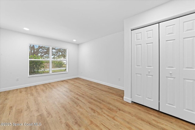 unfurnished bedroom with light wood-style floors, a closet, recessed lighting, and baseboards