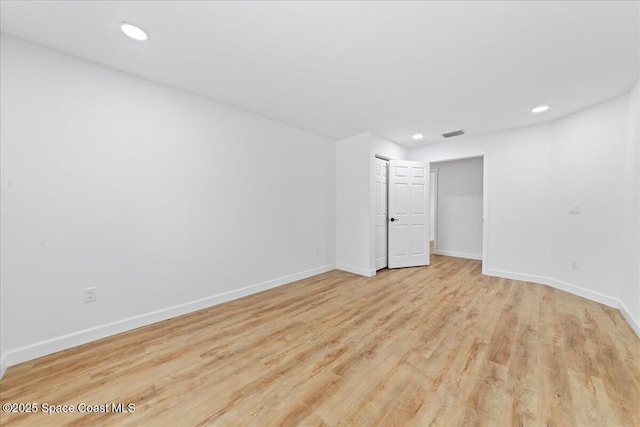 unfurnished room with baseboards, wood finished floors, visible vents, and recessed lighting