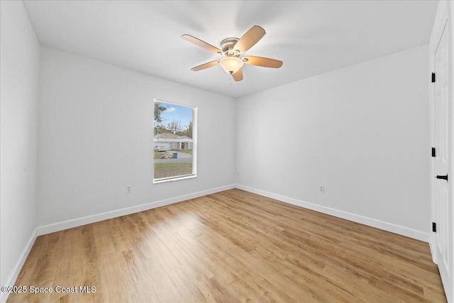 spare room with light wood-type flooring, baseboards, and a ceiling fan