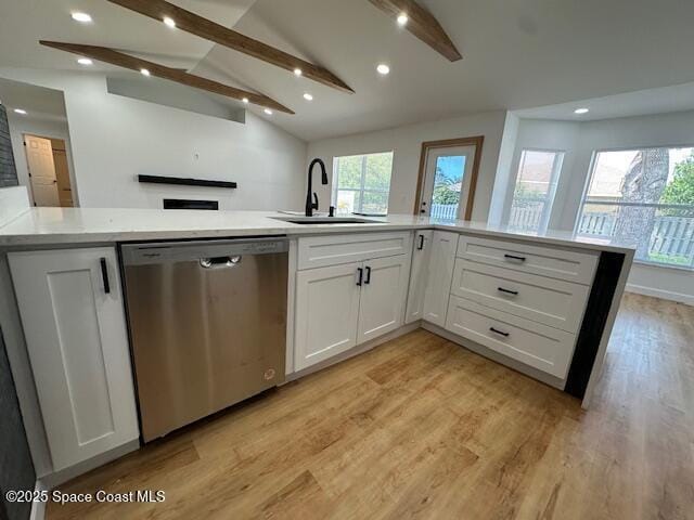 kitchen featuring vaulted ceiling with beams, light wood finished floors, light countertops, stainless steel dishwasher, and white cabinetry