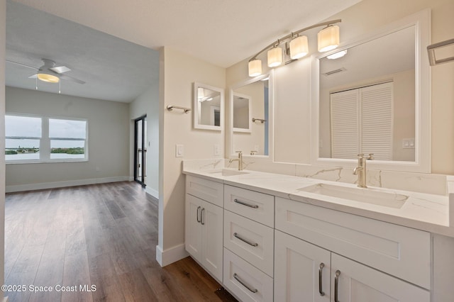 full bath with double vanity, wood finished floors, a sink, and a ceiling fan