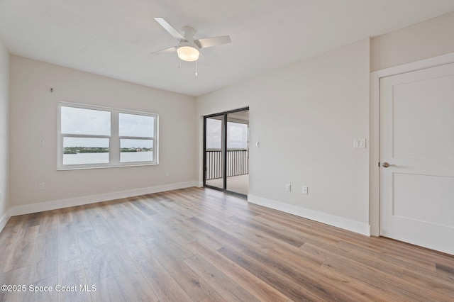 spare room with ceiling fan, light wood-type flooring, and baseboards