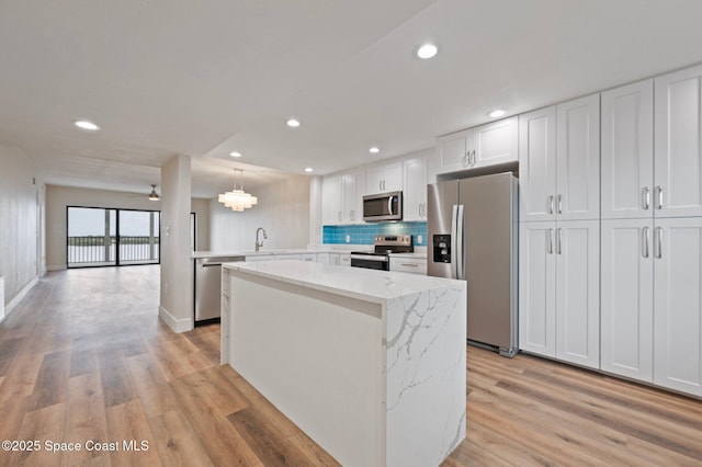 kitchen featuring stainless steel appliances, a sink, light wood finished floors, and a kitchen island