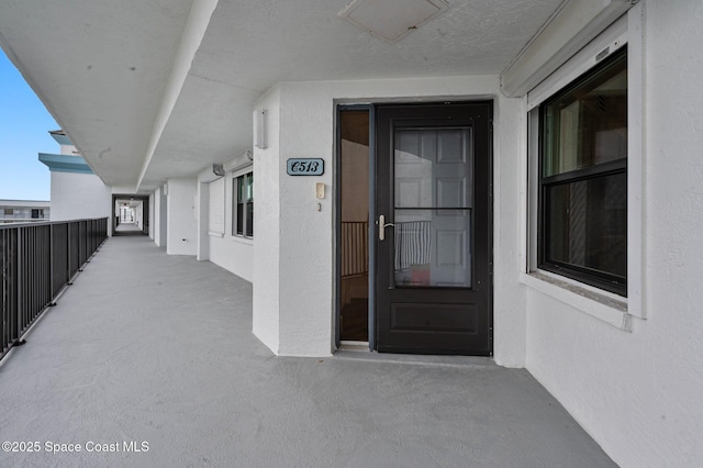 property entrance with a balcony and stucco siding