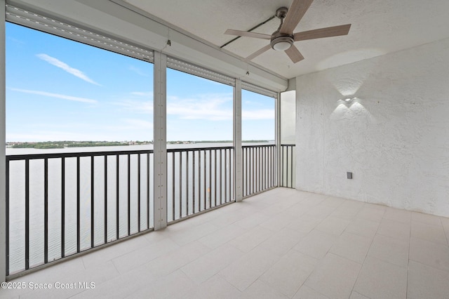 unfurnished sunroom featuring a water view and ceiling fan