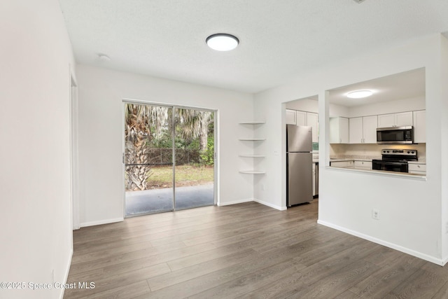 kitchen with baseboards, light countertops, appliances with stainless steel finishes, wood finished floors, and white cabinetry