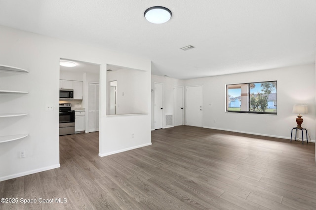 unfurnished living room with visible vents, baseboards, and wood finished floors