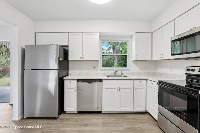 kitchen with white cabinetry, light wood finished floors, appliances with stainless steel finishes, and a sink