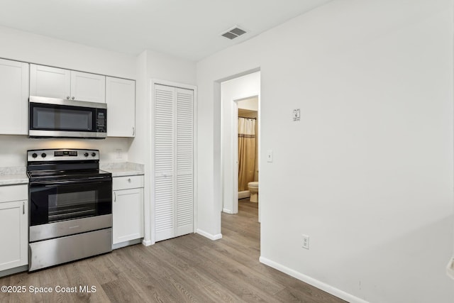 kitchen featuring visible vents, stainless steel appliances, light countertops, white cabinetry, and light wood-type flooring