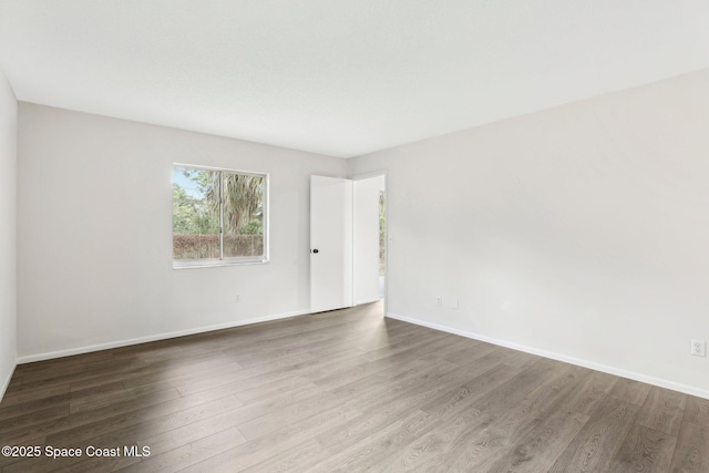 spare room with baseboards and wood finished floors