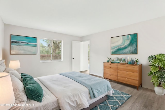 bedroom featuring light wood finished floors and baseboards